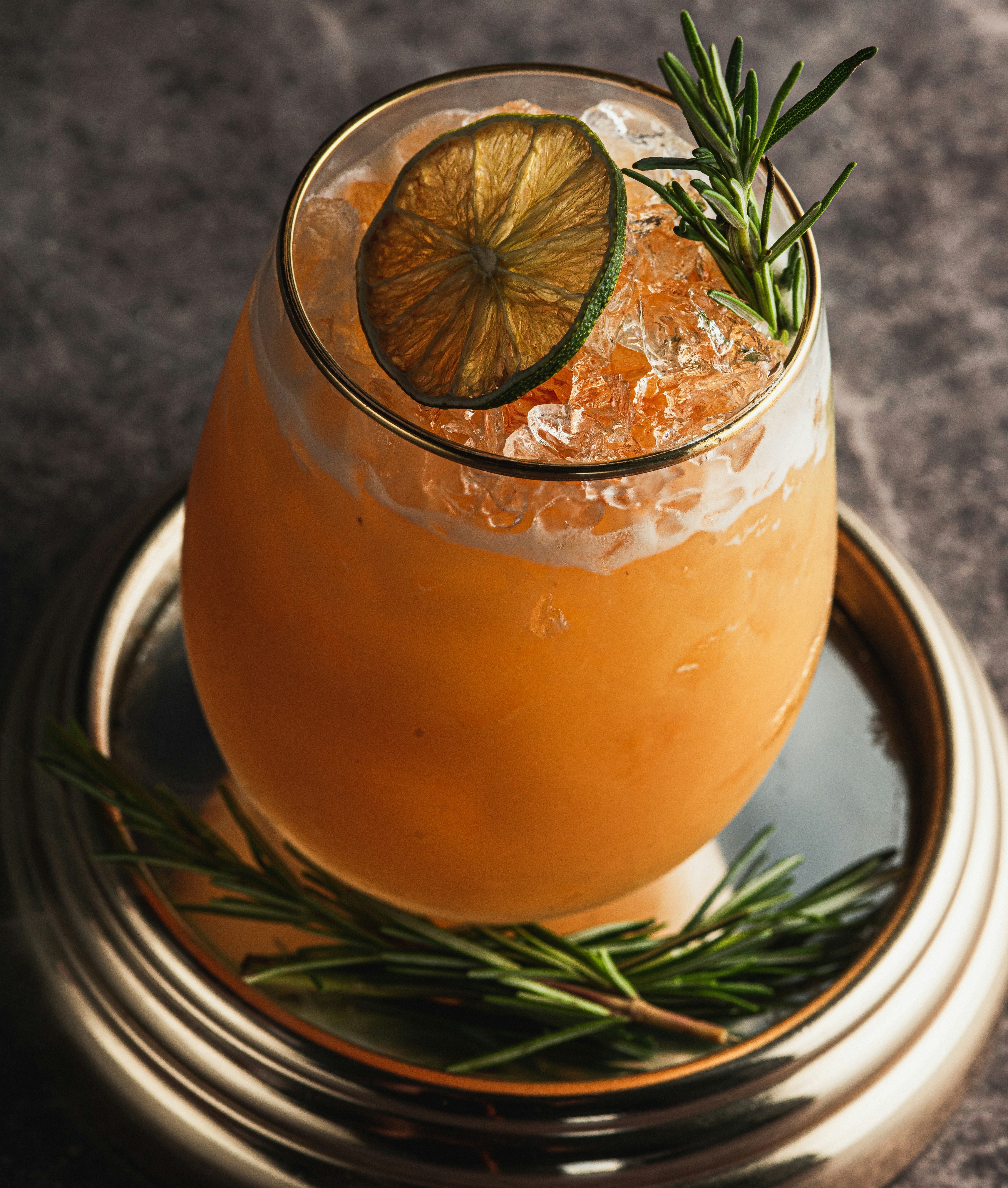  an orange citus liqour bevrage with an orange fruit slice and pine needles 