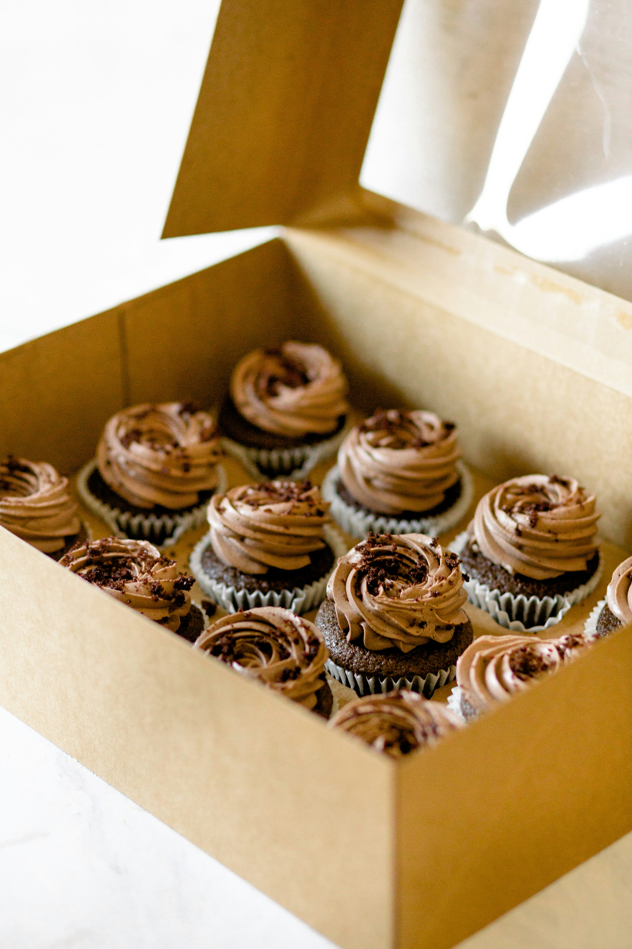 box of 12 decorated chocolate cupcakes in a beige to go box