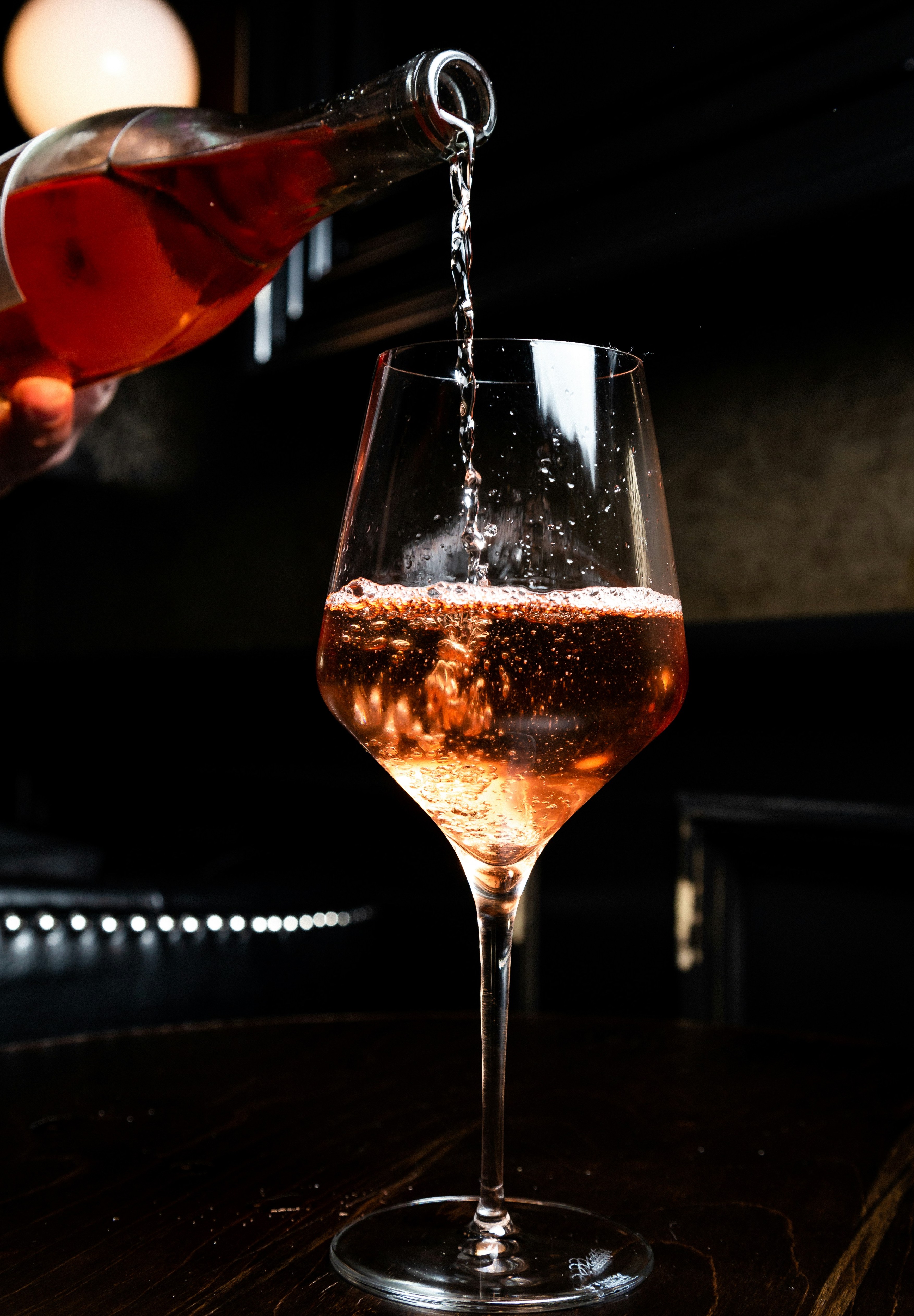   a half full glass of red wine being poured freshley from the bottle 